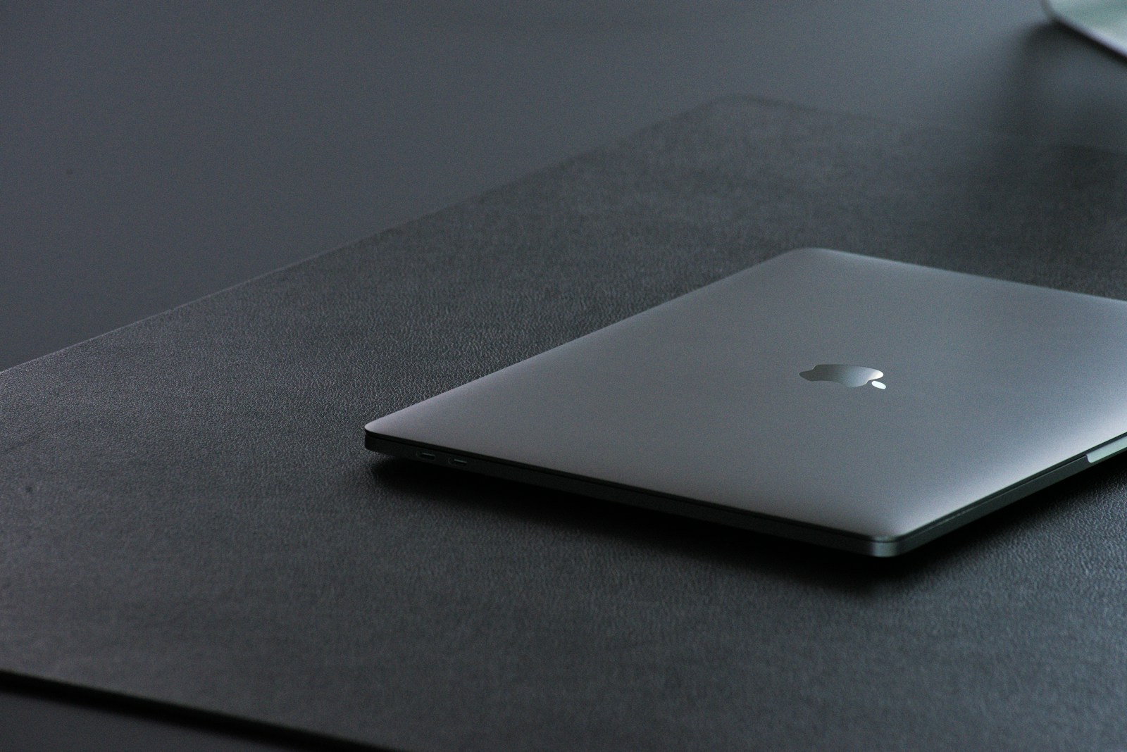 Silver MacBook resting on a dark textured surface